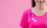Breast cancer awareness month, Woman in pink t-shirt with satin pink ribbon on her chest, supporting symbol of breast cancer awareness campaign in October.